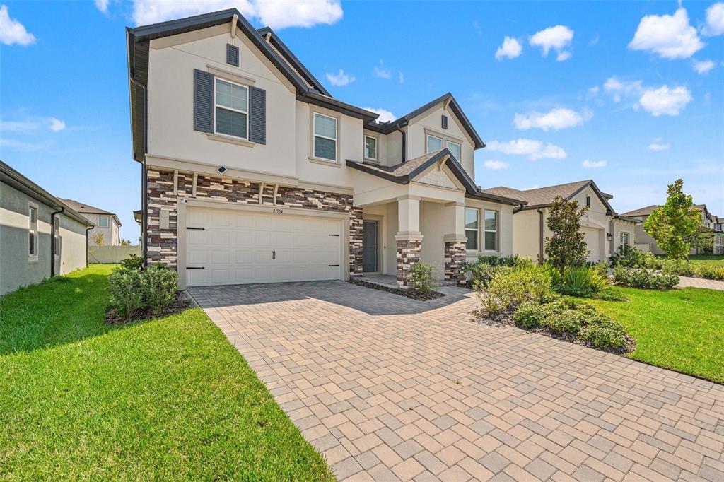 A two-story house with a stone-accented facade, a paved driveway, and a two-car garage — 31954 SAPNA CHIME DRIVE, WESLEY CHAPEL, FL