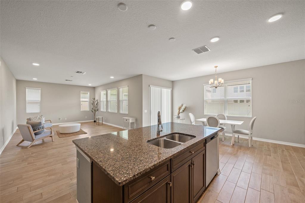 An open-concept kitchen with a granite island overlooks a living area and dining space — 31954 SAPNA CHIME DRIVE, WESLEY CHAPEL, FL
