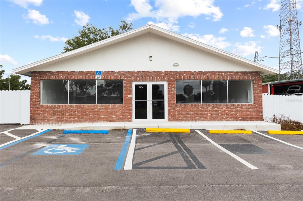 A single-story brick commercial building features a front entrance and a paved parking lot — 7604 E BROADWAY AVENUE, TAMPA, FL