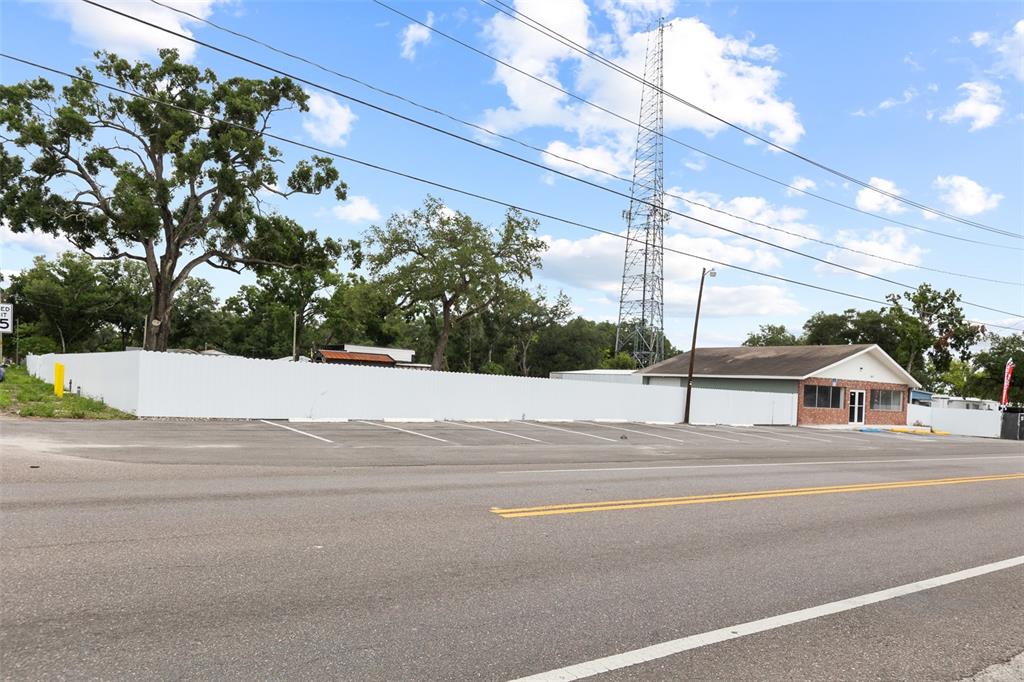 A commercial building with a white privacy fence and a tall communication tower behind it — 7604 E BROADWAY AVENUE, TAMPA, FL