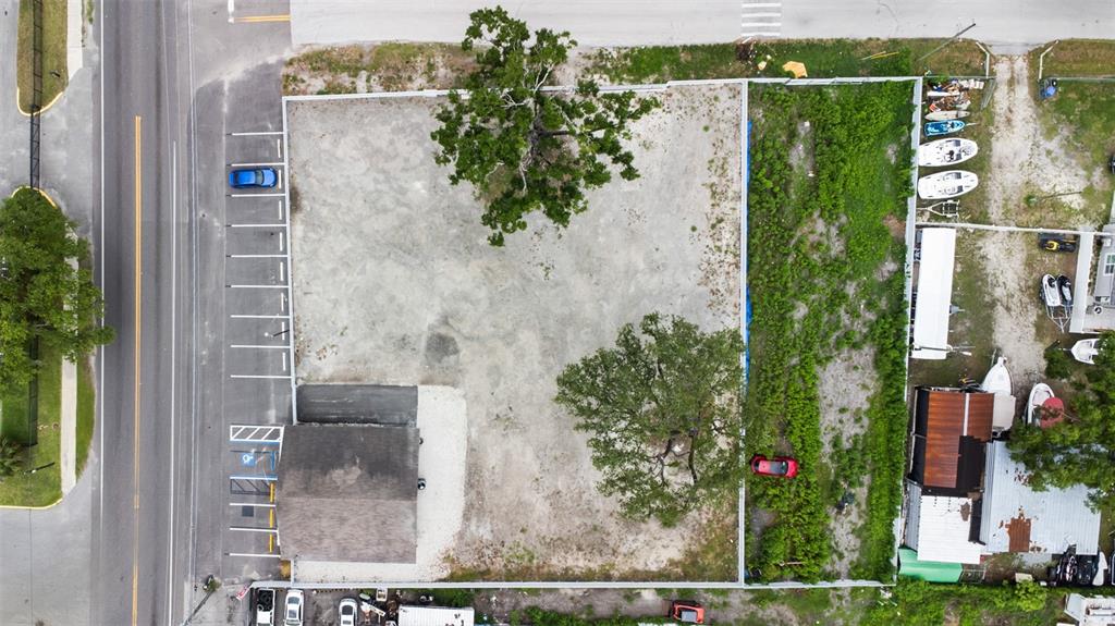 An aerial view shows a vacant rectangular lot with two large trees and a building — 7604 E BROADWAY AVENUE, TAMPA, FL