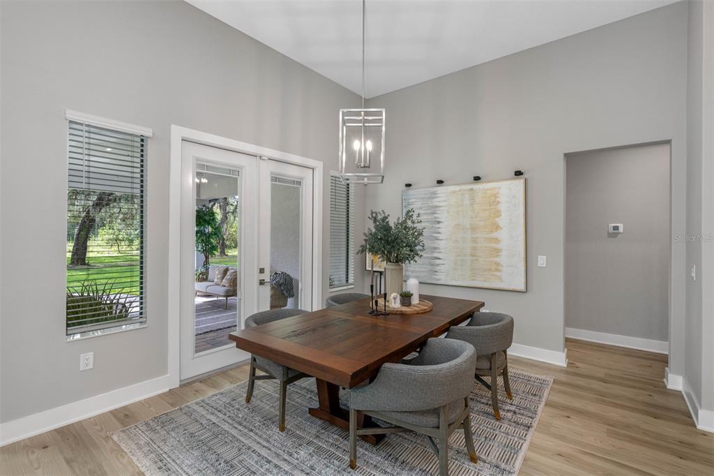A dining room features a wooden table, gray chairs, a pendant light, and glass doors — 13055 OLDENBURG DRIVE, HUDSON, FL