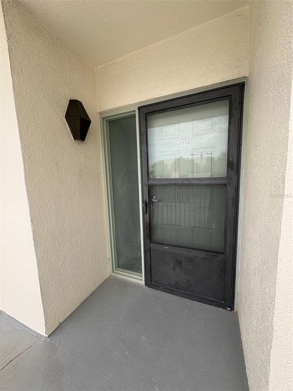 The exterior entrance features a gray porch, a black storm door, and a wall-mounted light — 250 WOODETTE DRIVE UNIT A, DUNEDIN, FL