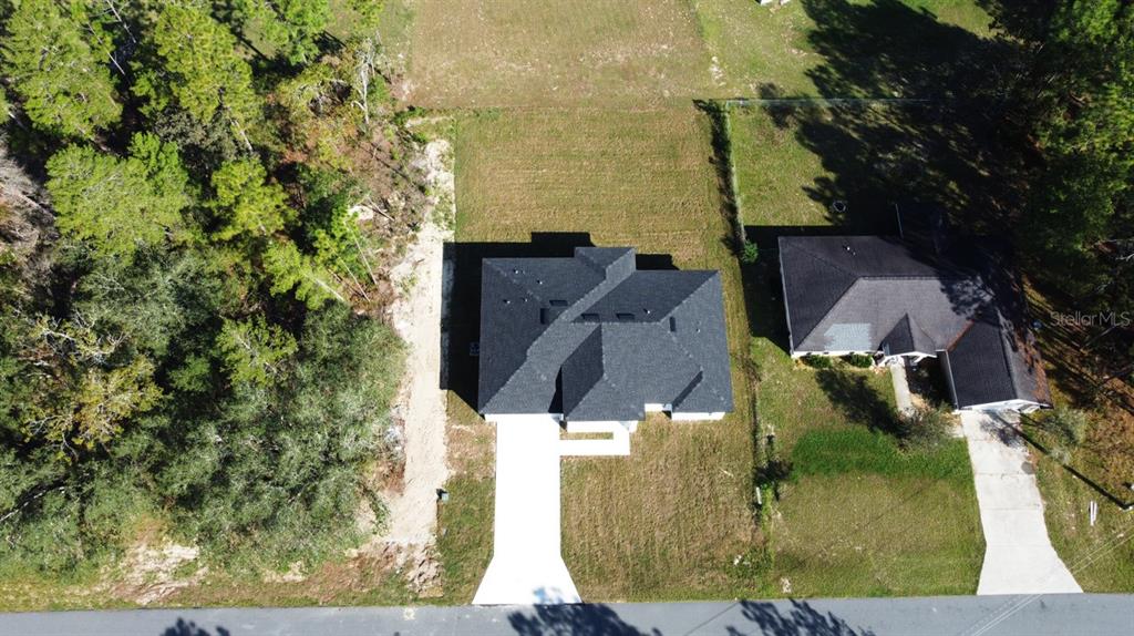 An aerial view shows a new house with a dark roof and concrete driveway — 6243 SW 133RD STREET ROAD, OCALA, FL