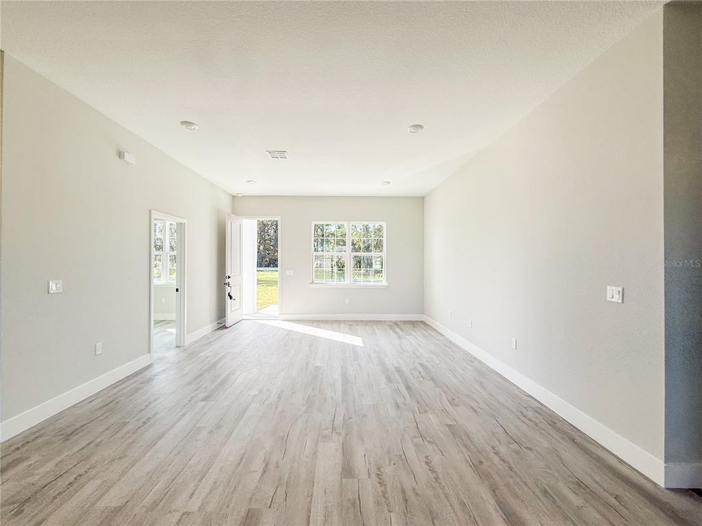 An empty room with light-colored walls, wood-look flooring, recessed lighting, and a glass-paneled door — 6243 SW 133RD STREET ROAD, OCALA, FL