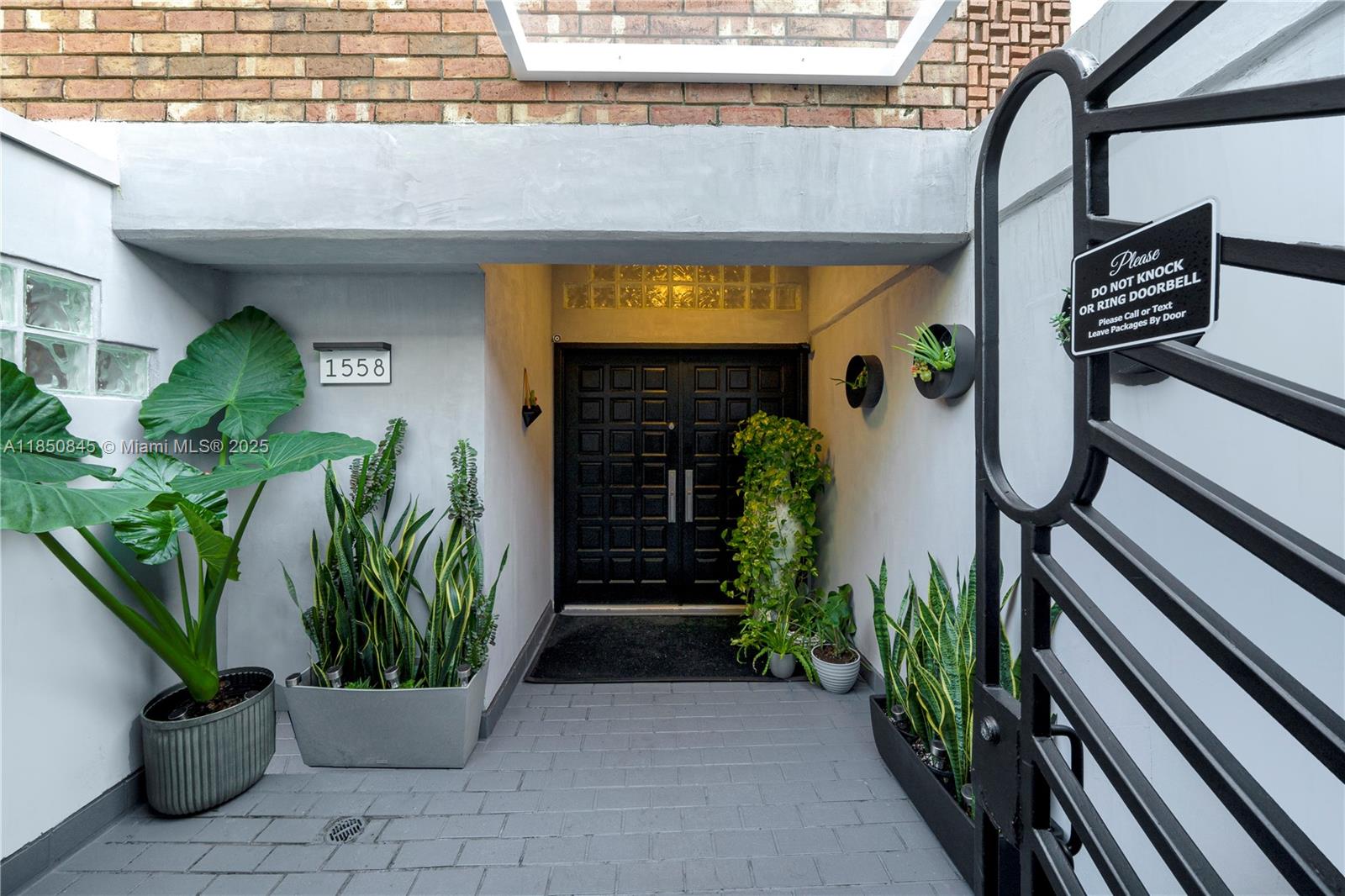 A recessed entryway features a black double door, potted plants, and a brick-paved floor — 1558 NE Quayside Ter # D10, Miami FL 33138, MIAMI, FL