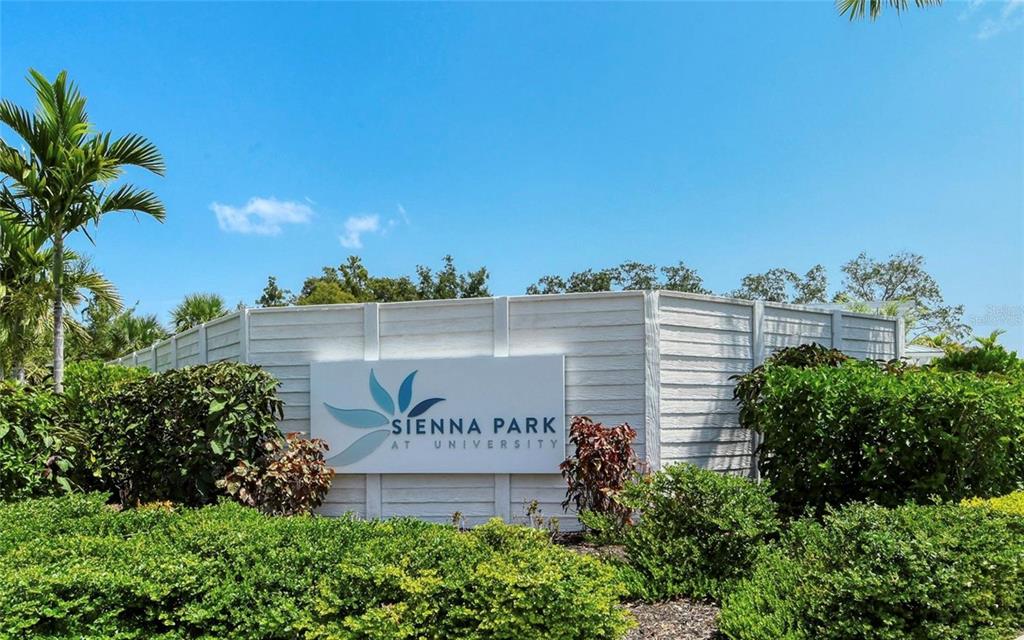 A white sign for Sienna Park at University stands in front of a privacy fence — 4020 VIA SIENNA CIRCLE, SARASOTA, FL