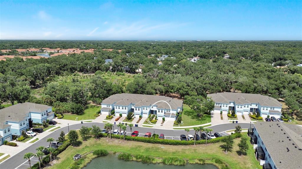 An aerial view shows multi-story residential townhomes with a pond and surrounding trees — 4020 VIA SIENNA CIRCLE, SARASOTA, FL