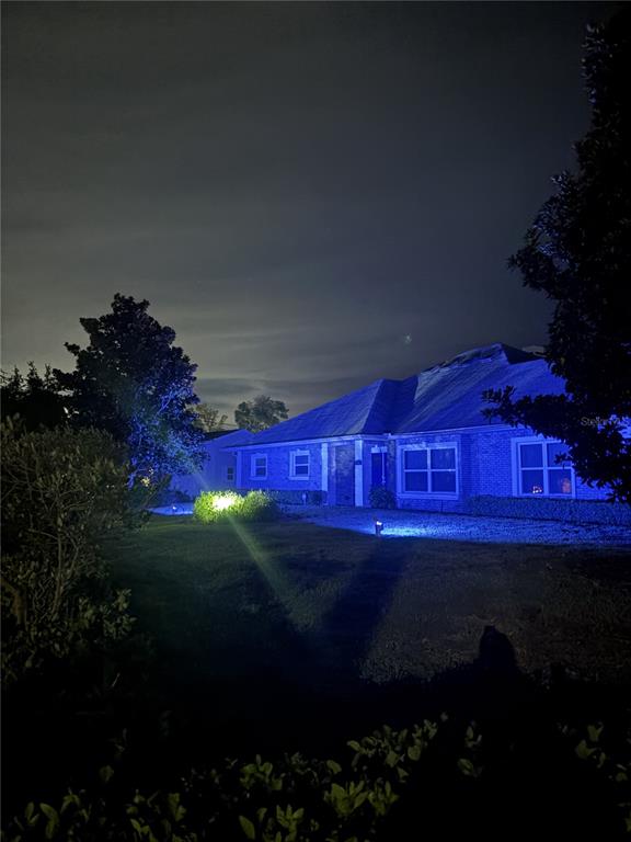 A single-story brick house at night illuminated by blue landscape lighting — 1520 SE PINWHEEL DRIVE, CRYSTAL RIVER, FL
