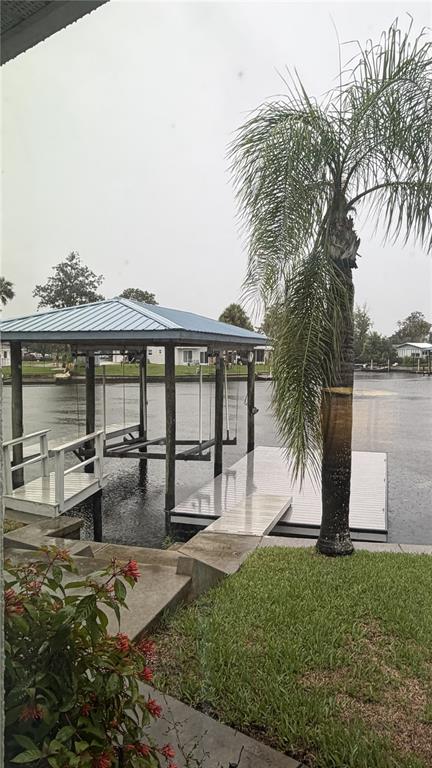 A boat lift and dock sit on a canal next to a palm tree — 1520 SE PINWHEEL DRIVE, CRYSTAL RIVER, FL