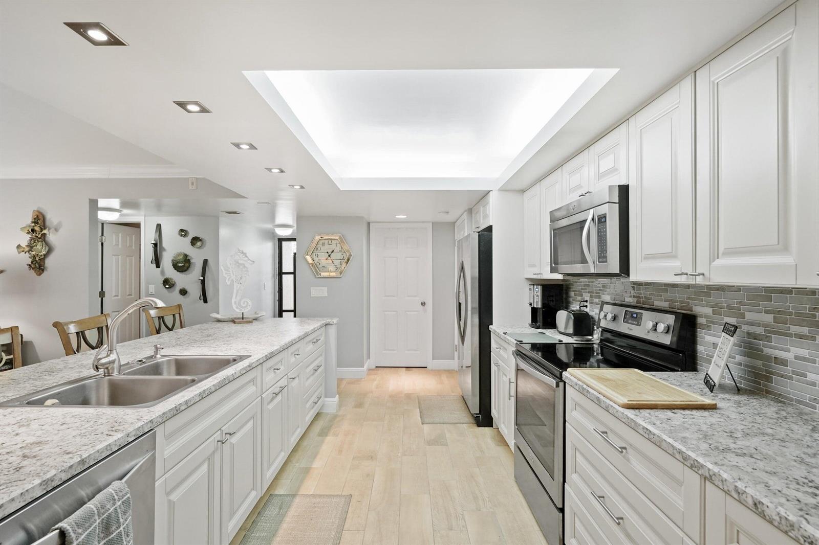 A kitchen features white cabinets, granite countertops, stainless steel appliances, and a recessed ceiling light — 2255 Lindell Boulevard # 4105, Delray Beach FL 33444, DELRAY BEACH, FL