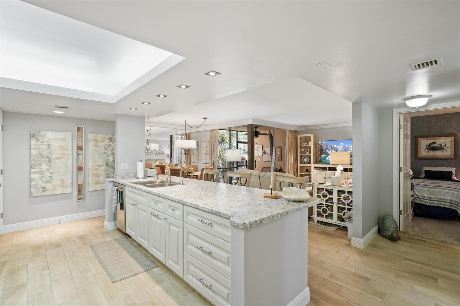 A kitchen with white cabinets and granite countertops opens into a living area and bedroom — 2255 Lindell Boulevard # 4105, Delray Beach FL 33444, DELRAY BEACH, FL