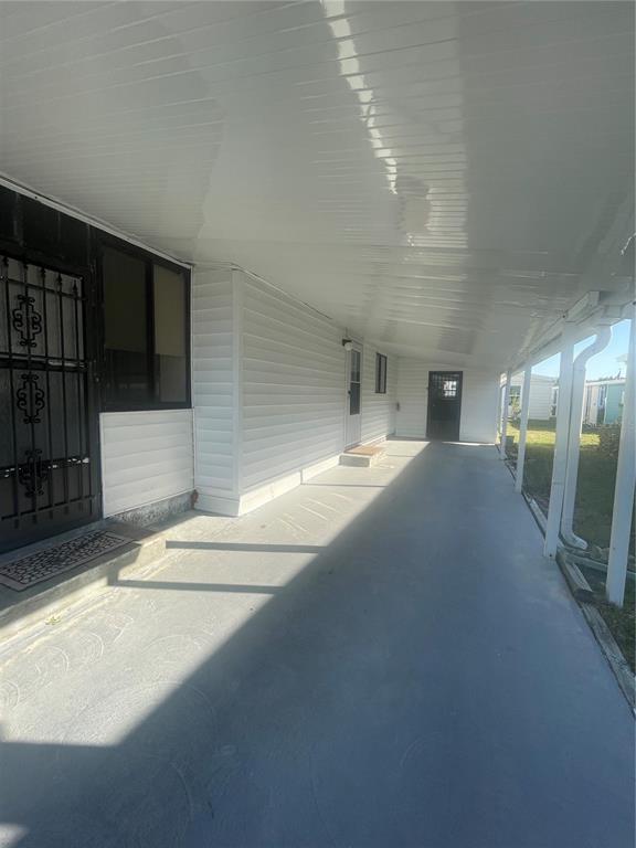 A covered concrete carport runs alongside the side of a white vinyl-sided mobile home — 206 MONITOR DRIVE, FLAGLER BEACH, FL