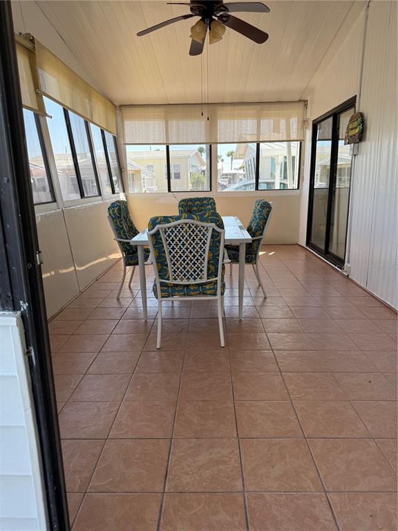 A sunroom features tile flooring, a dining set, and large windows with roller shades — 206 MONITOR DRIVE, FLAGLER BEACH, FL