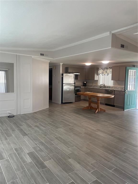 An open-concept kitchen and living area features gray wood-look tile flooring and neutral cabinetry — 206 MONITOR DRIVE, FLAGLER BEACH, FL