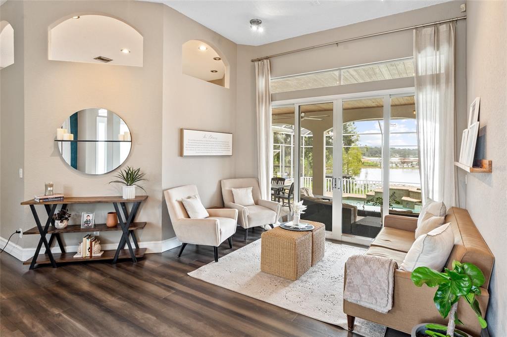 A living room features a sofa, two armchairs, a console table, and sliding glass doors — 11210 CRESCENT BAY BOULEVARD, CLERMONT, FL