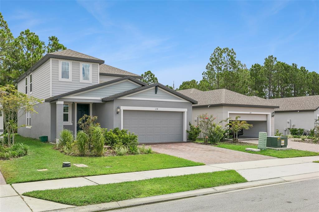 A two-story gray house with a two-car garage and a paved driveway — 128 LOST BALL DRIVE, DAYTONA BEACH, FL