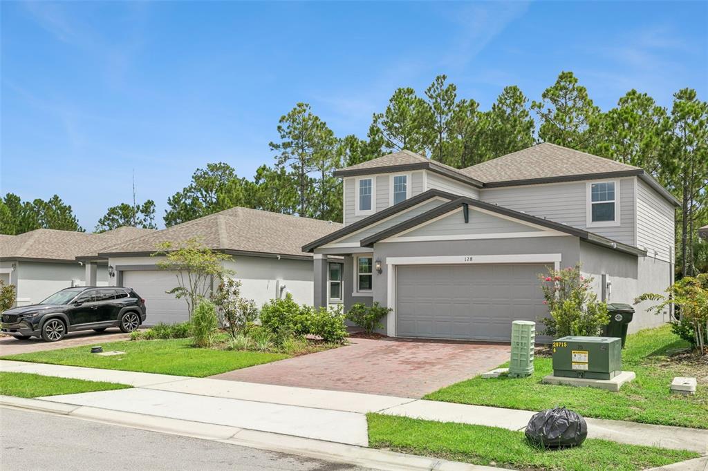 A two-story suburban house with a gray exterior, a two-car garage, and a paved driveway — 128 LOST BALL DRIVE, DAYTONA BEACH, FL
