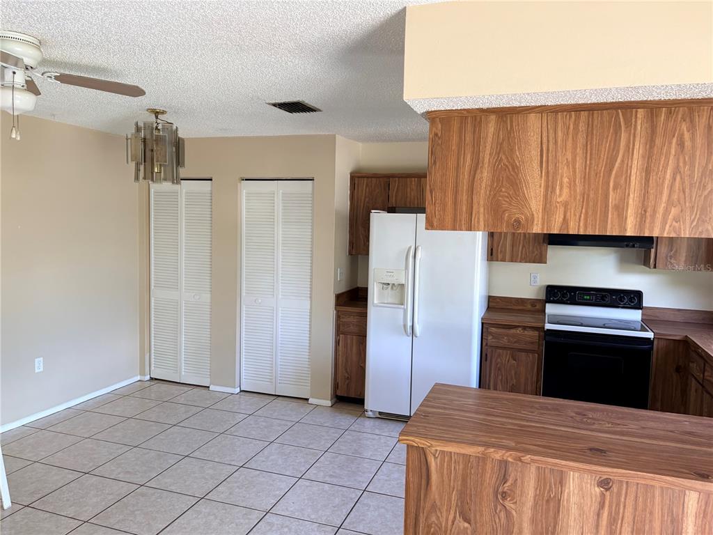 A kitchen and dining area with wood-look cabinets, white appliances, and tiled flooring — 8907 WAYWARD CIRCLE, HUDSON, FL