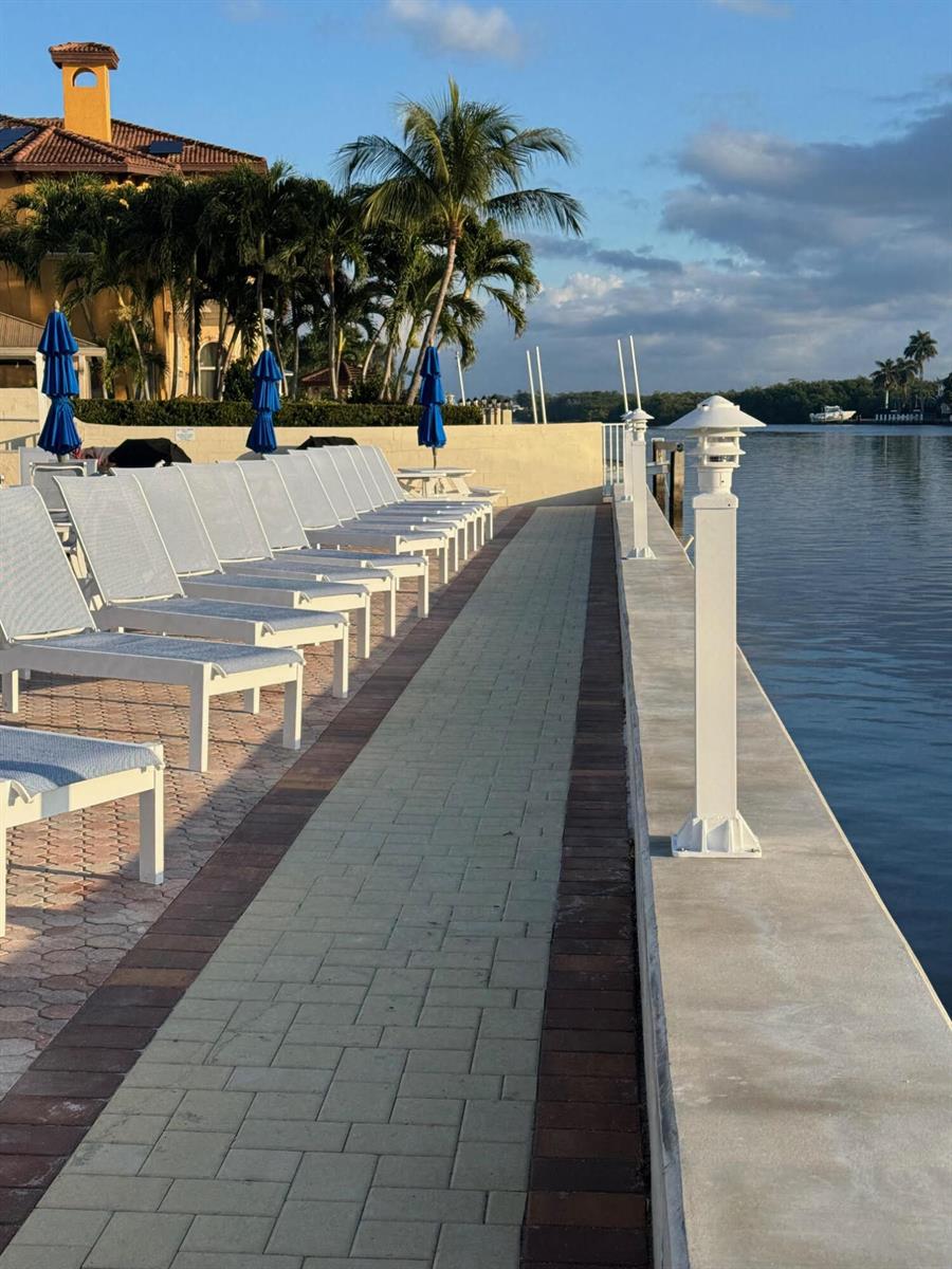 A row of lounge chairs sits on a paved patio beside a waterfront seawall — 632 Snug Harbor Drive # D3, Boynton Beach FL 33435, BOYNTON BEACH, FL