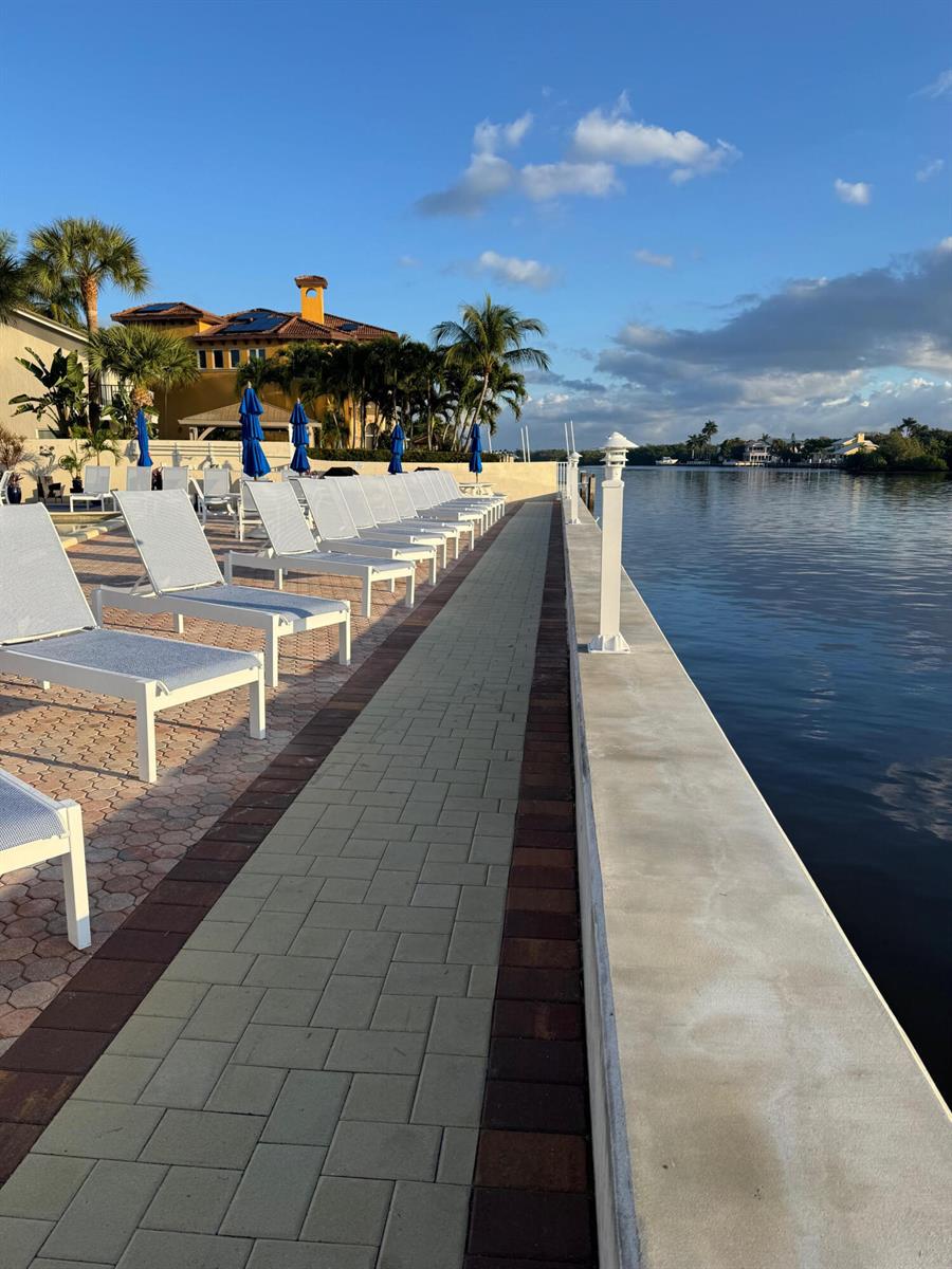 A swimming pool area features lounge chairs on a paved deck with palm trees nearby — 632 Snug Harbor Drive # D3, Boynton Beach FL 33435, BOYNTON BEACH, FL