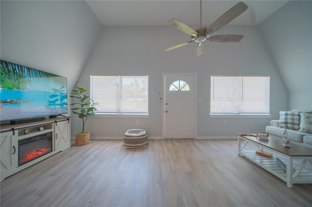 A living room features light wood flooring, a vaulted ceiling, a ceiling fan, and windows — 501 PAMETO ROAD, NOKOMIS, FL