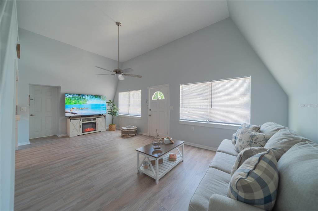 A living room features light-colored wood flooring, a vaulted ceiling, a ceiling fan, and windows — 501 PAMETO ROAD, NOKOMIS, FL