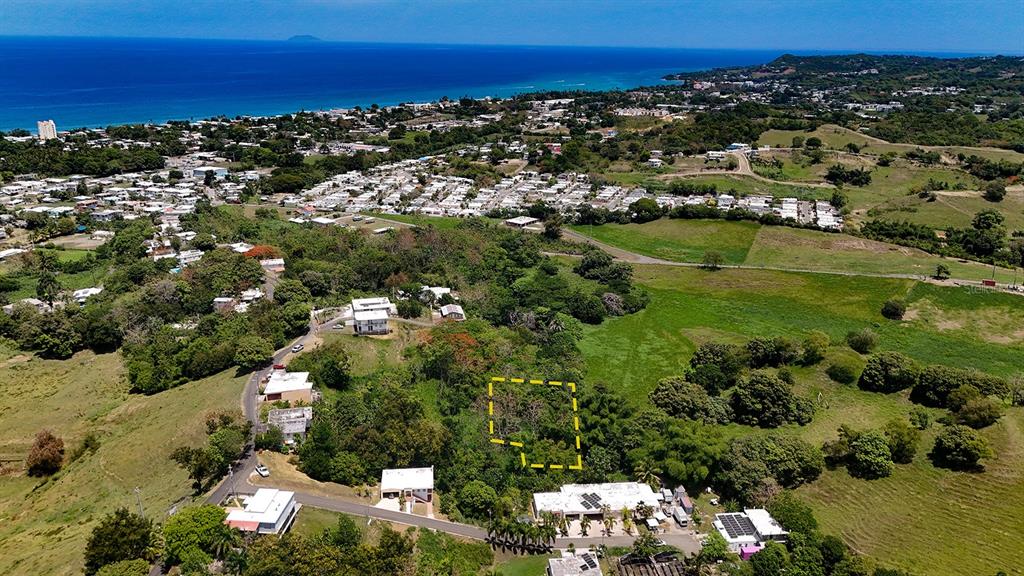 An aerial view shows a rectangular plot of land outlined in yellow near residential homes — CARR 115 KM HM 11.3, RINCON, PR