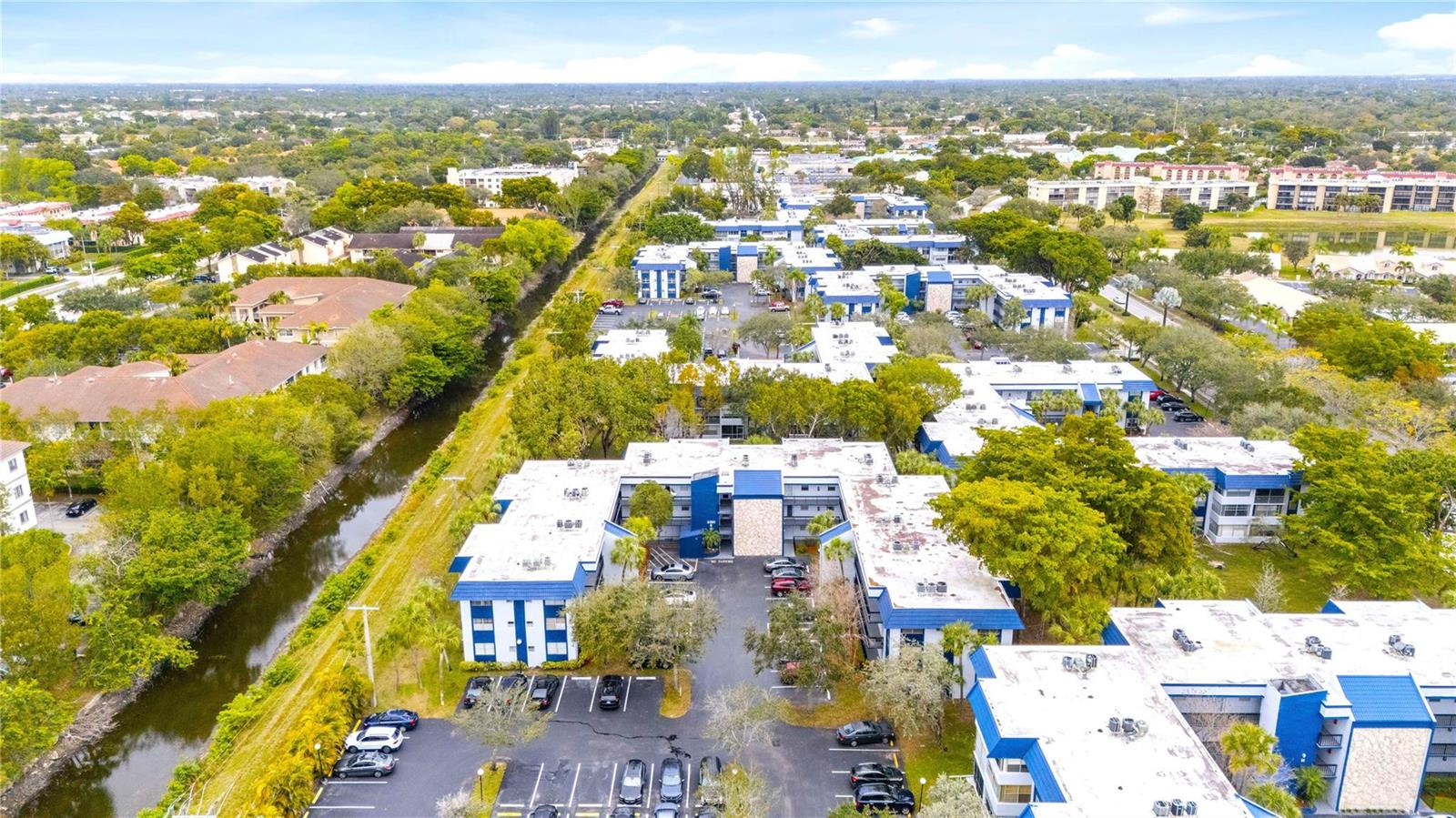 A white kitchen with tile flooring opens into a carpeted living area with a balcony — 3150 Holiday Springs Boulevard # 308, Margate FL 33063, MARGATE, FL