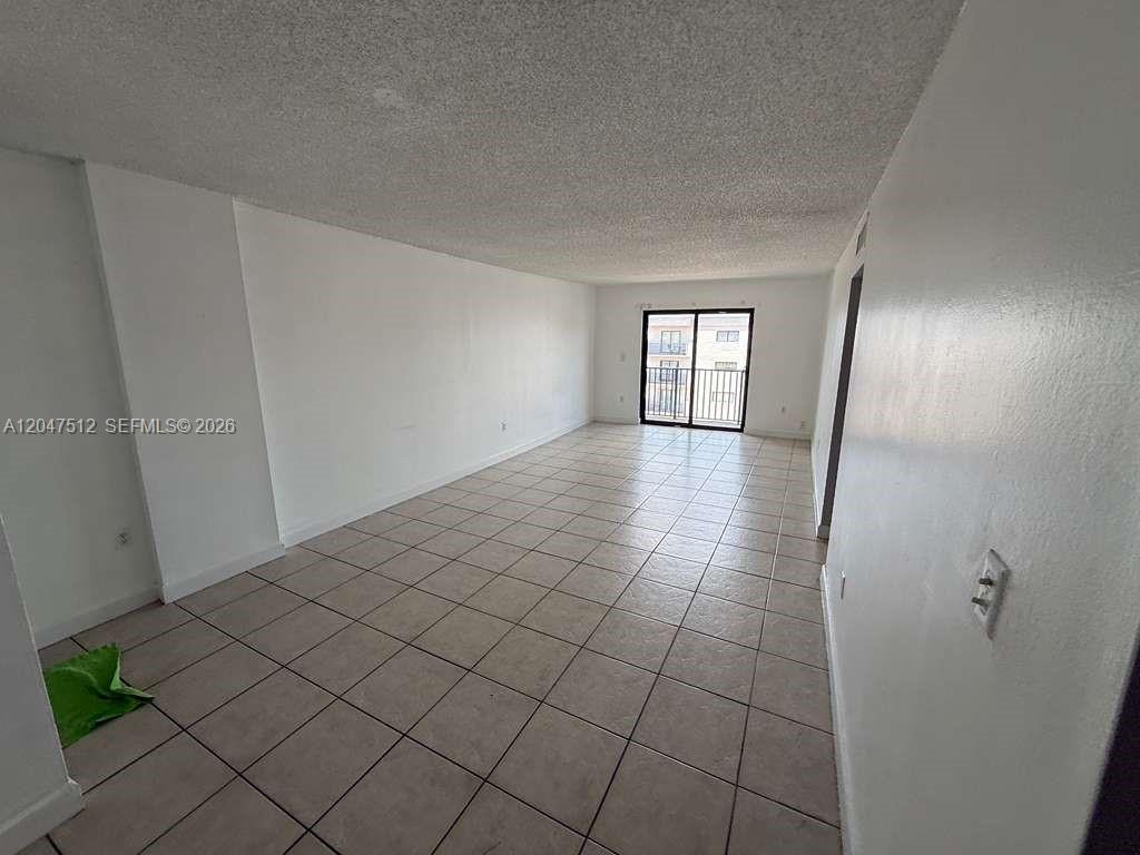 An empty room with white walls, tile flooring, and a sliding glass door to a balcony — 6950 W 6th Ave # 509, Hialeah FL 33014, HIALEAH, FL