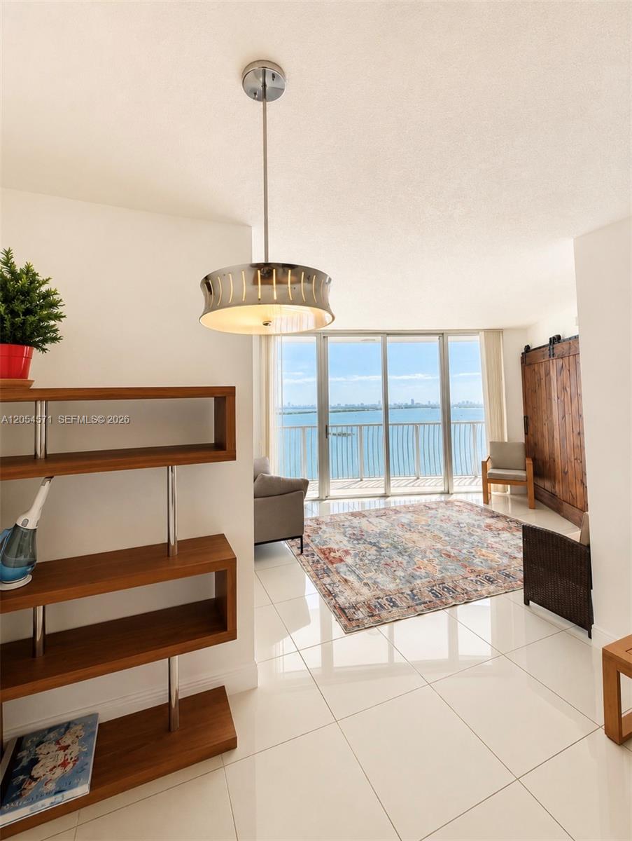 A living room features white tile floors, a modern pendant light, and a balcony view — 1750 N Bayshore Dr # 4201, Miami FL 33132, MIAMI, FL
