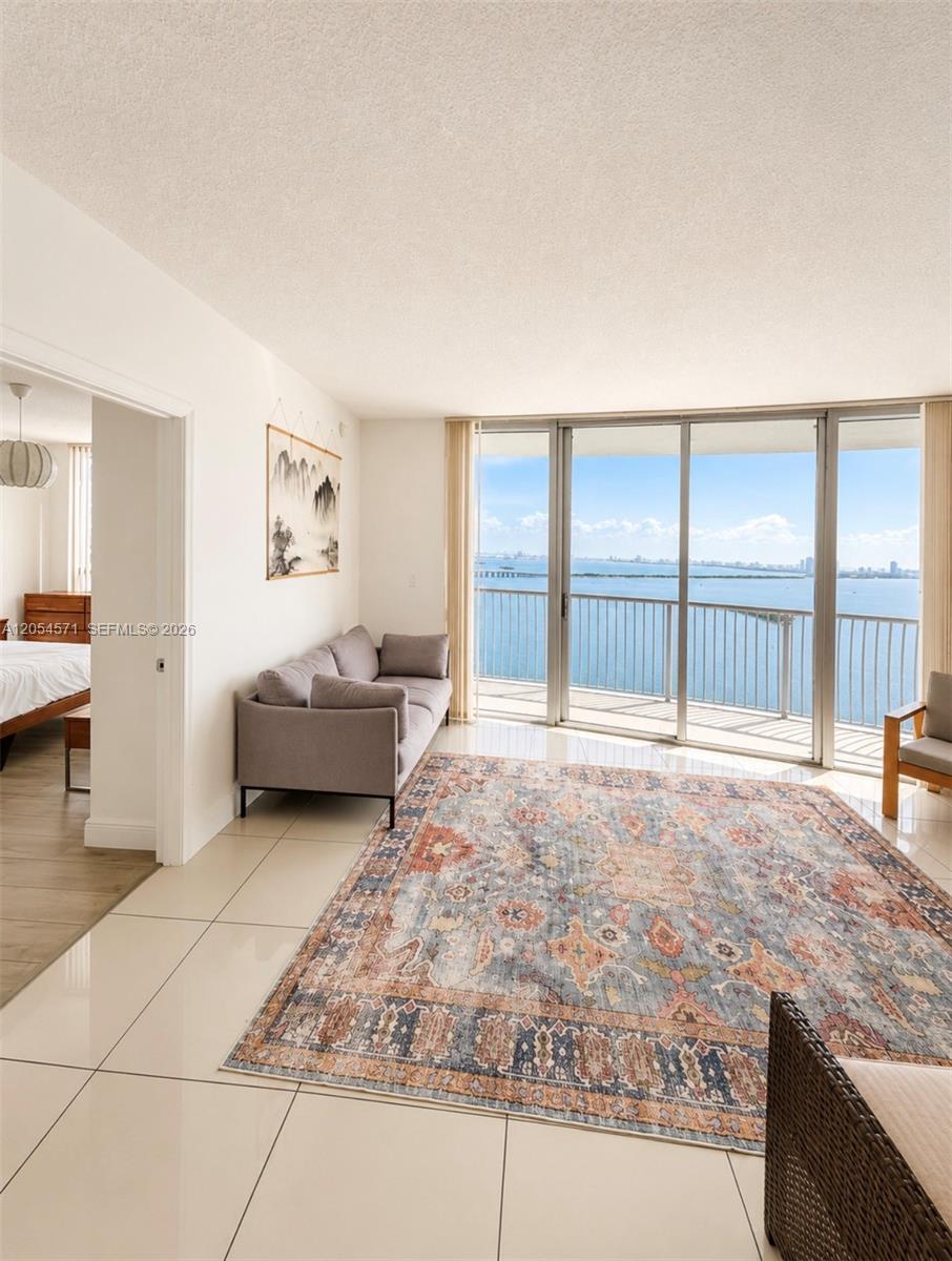 A living room with tile floors, a patterned rug, and a balcony overlooking the ocean — 1750 N Bayshore Dr # 4201, Miami FL 33132, MIAMI, FL