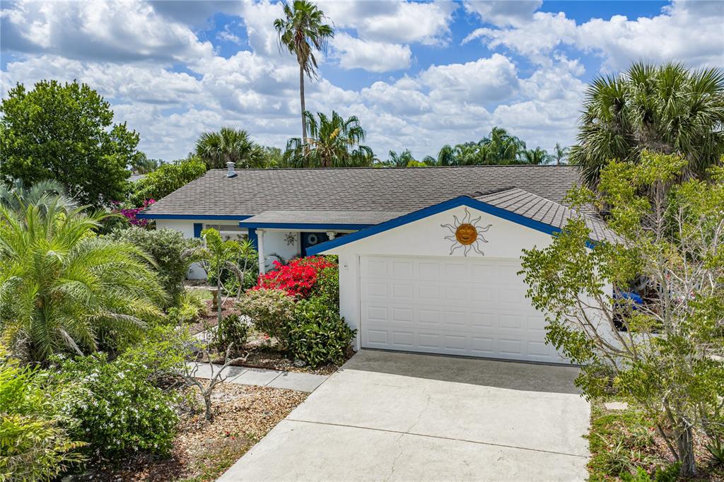 A single-story house with a white garage, blue trim, and a sun decoration on the gable — 906 SAGO PALM WAY, APOLLO BEACH, FL