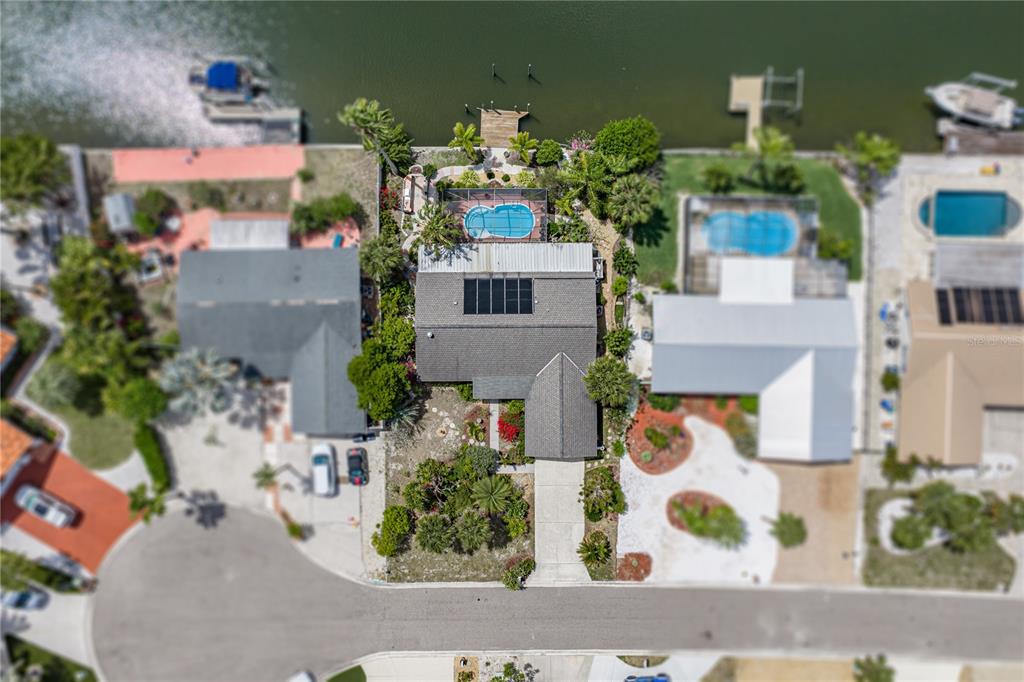 An aerial view shows a waterfront house with a pool, solar panels, and a dock — 906 SAGO PALM WAY, APOLLO BEACH, FL