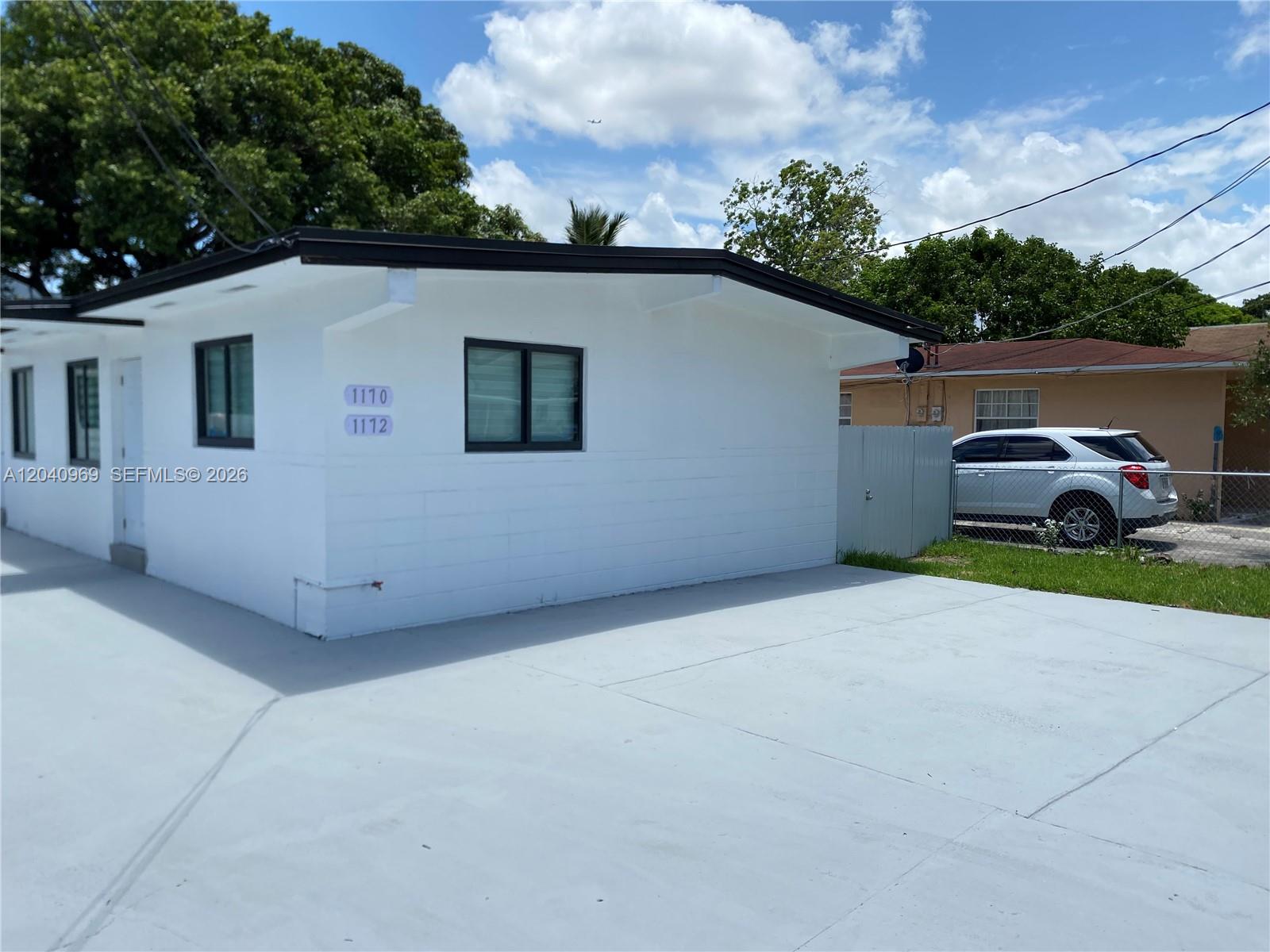 A white, single-story building with a flat roof and a paved driveway sits under a blue sky — 1170 NW 25th St # 1170, Miami FL 33127, MIAMI, FL