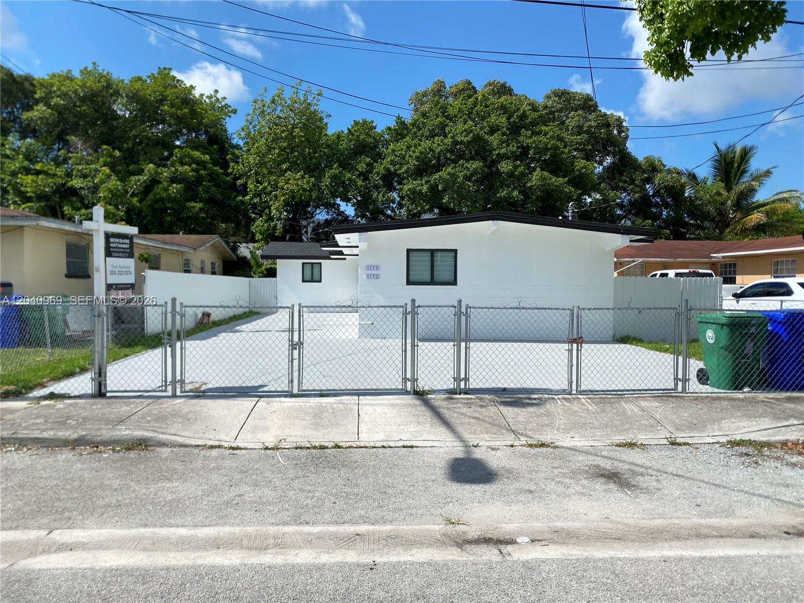 A white single-story house with a chain-link fence and a concrete driveway in front — 1170 NW 25th St # 1170, Miami FL 33127, MIAMI, FL