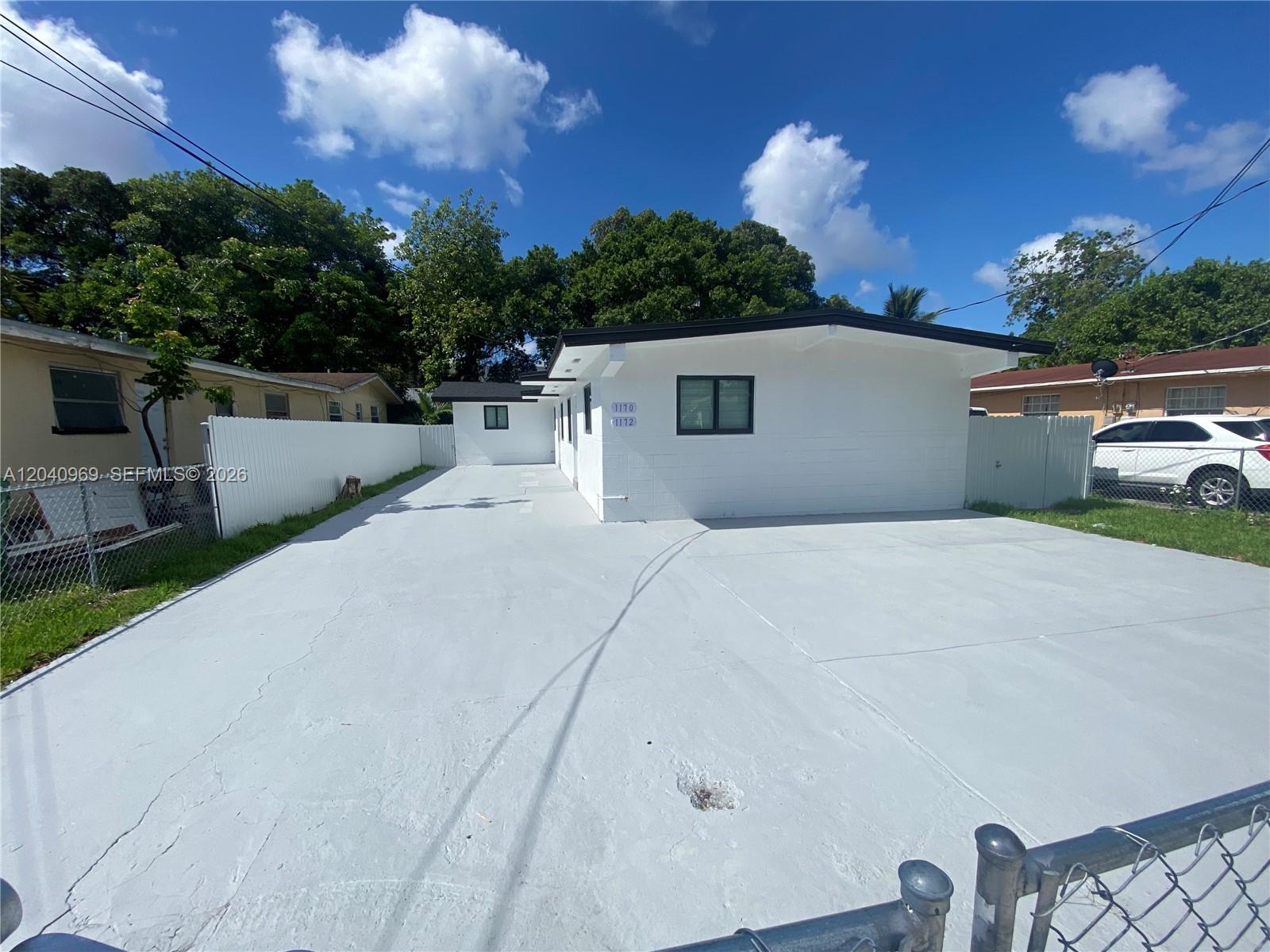 A white single-story house with a large concrete driveway and a chain-link fence — 1170 NW 25th St # 1170, Miami FL 33127, MIAMI, FL