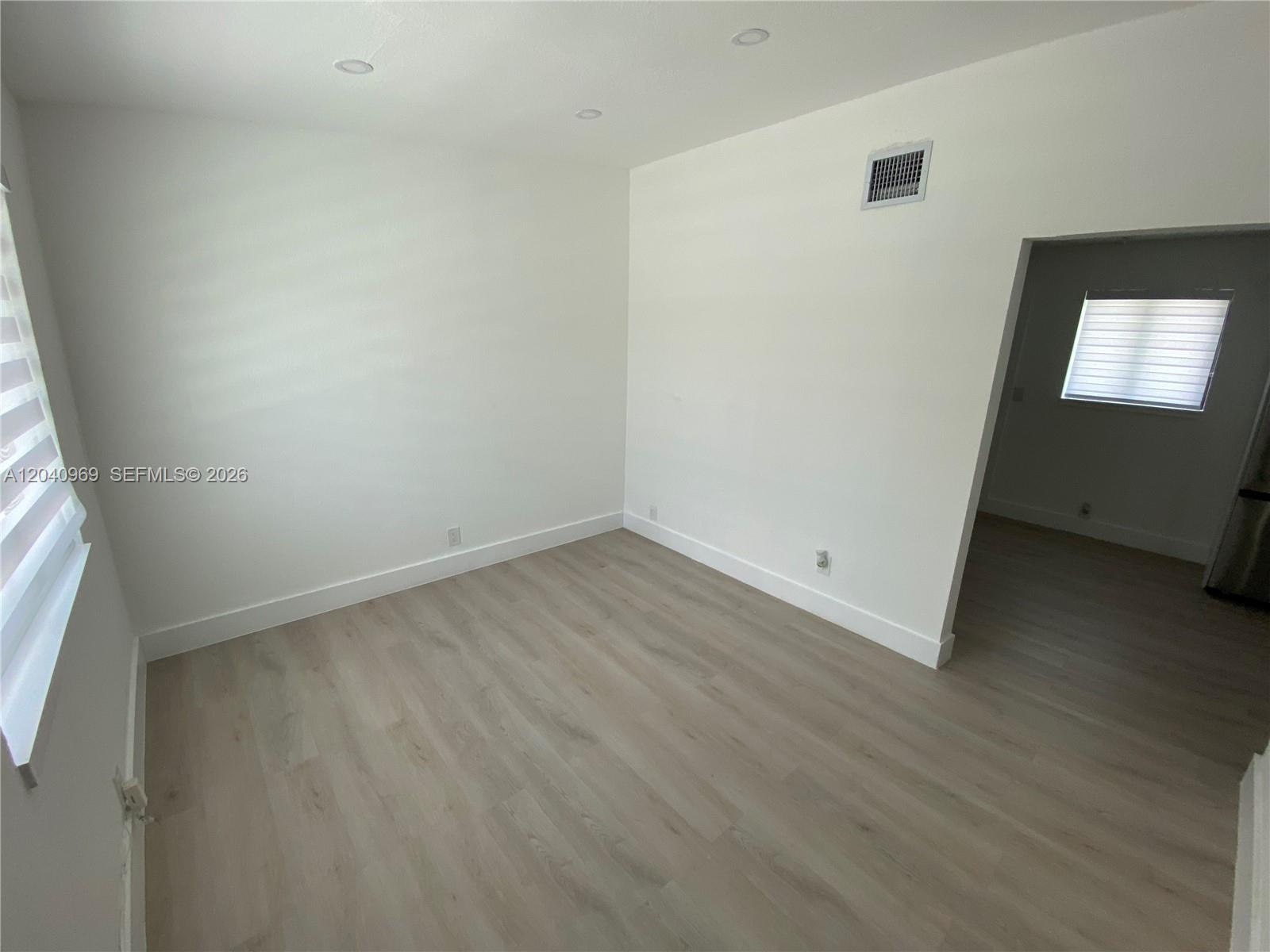 An empty room features light wood-look flooring, white walls, recessed lighting, and a doorway — 1170 NW 25th St # 1170, Miami FL 33127, MIAMI, FL