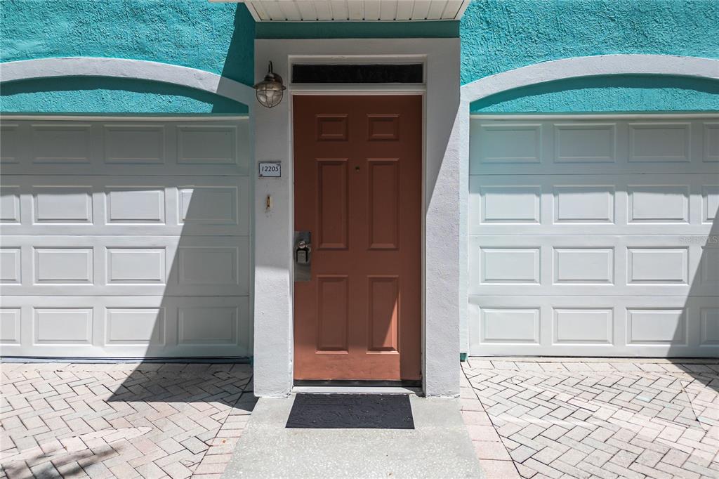 A brown front door is centered between two white garage doors on a turquoise building — 3019 BONFIRE BEACH DRIVE UNIT 205, KISSIMMEE, FL
