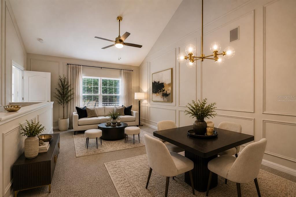 A living and dining area features vaulted ceilings, wainscoting, and a modern brass chandelier — 3019 BONFIRE BEACH DRIVE UNIT 205, KISSIMMEE, FL