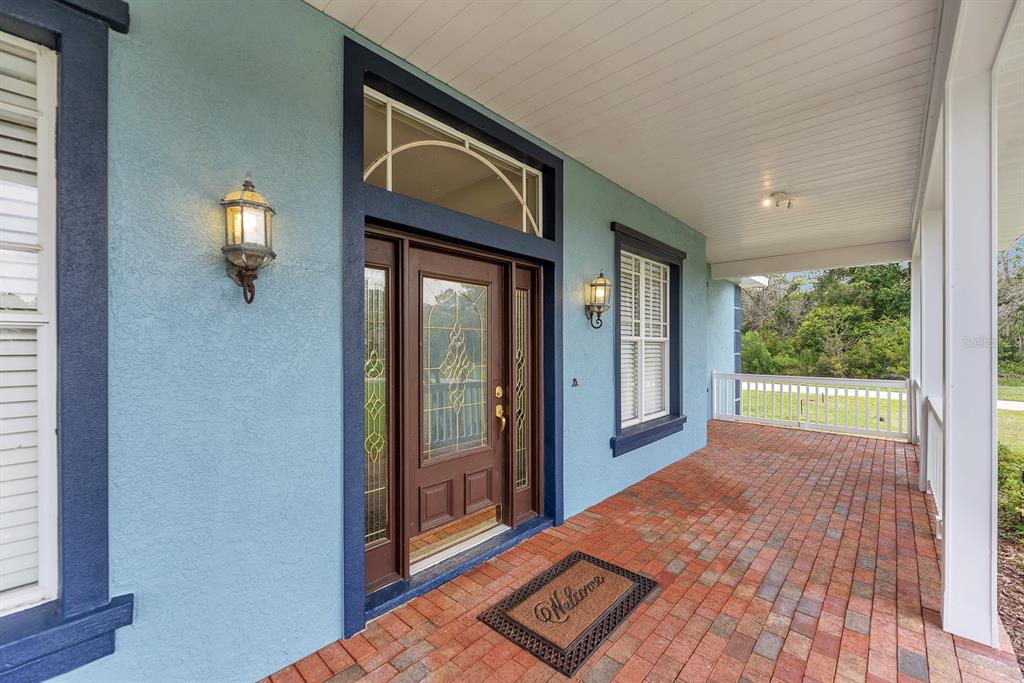 A covered brick porch leads to a front door with a transom and sidelights — 6023 KESTREL POINT AVENUE, LITHIA, FL