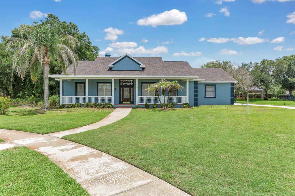 A blue single-story house with a white porch and a front walkway on a lawn — 6023 KESTREL POINT AVENUE, LITHIA, FL