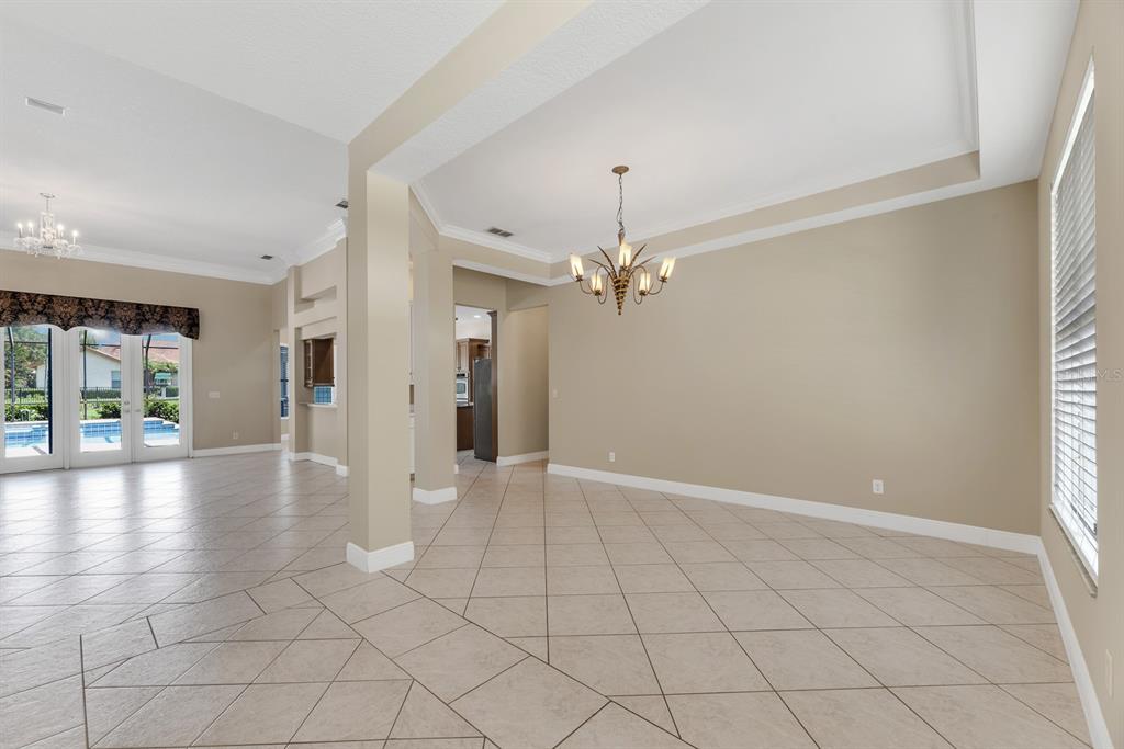 An open dining area features a chandelier, beige walls, and diagonal tile flooring — 6023 KESTREL POINT AVENUE, LITHIA, FL