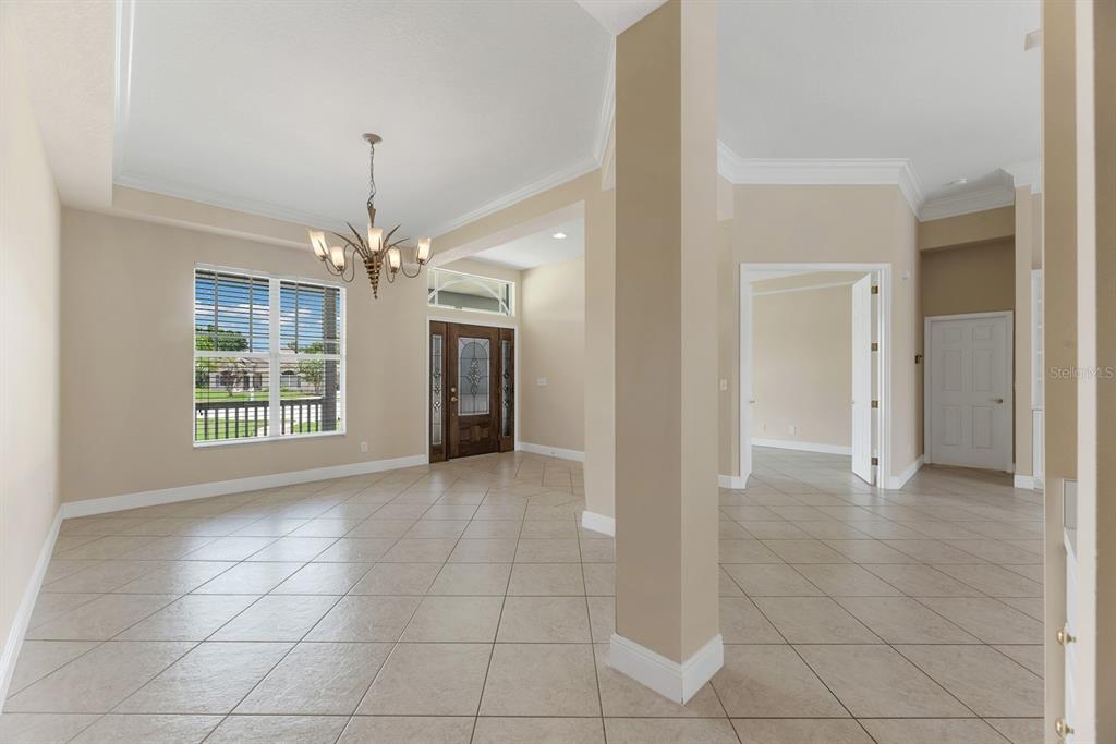 A spacious foyer with light tile flooring, a chandelier, and a front door with glass — 6023 KESTREL POINT AVENUE, LITHIA, FL
