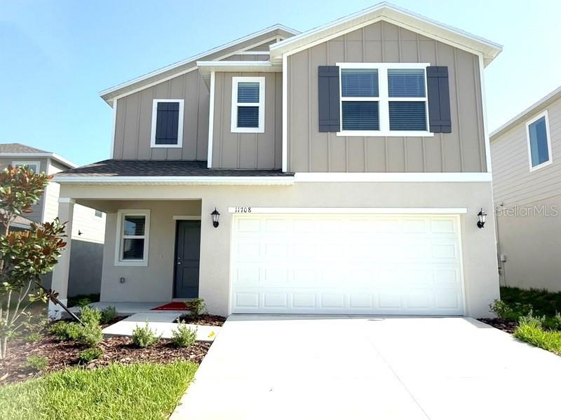 A two-story house features a light-colored exterior, a two-car garage, and dark window shutters — 11708 NOBLE BLOSSOM LOOP, DADE CITY, FL