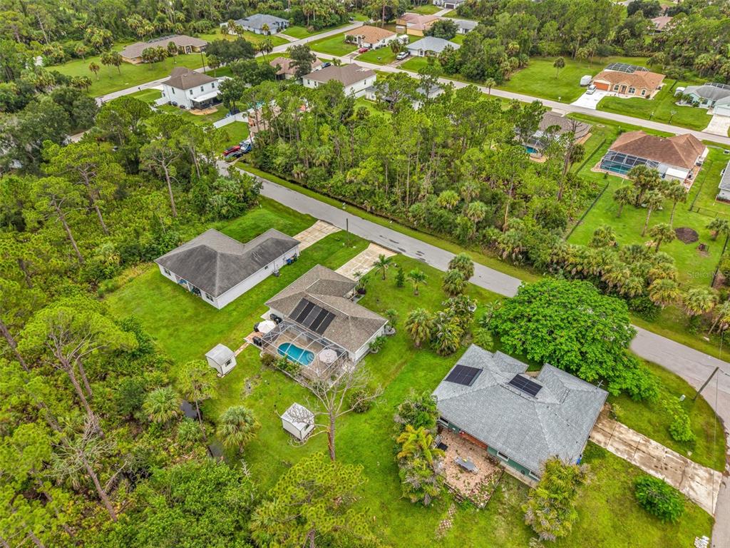 An aerial view shows several suburban houses with pools and yards surrounded by dense trees — 3178 ALBENGA LANE, NORTH PORT, FL