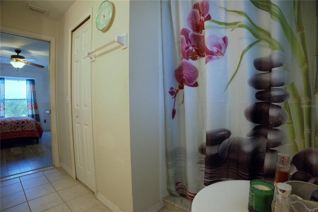 A bathroom features a shower curtain with orchid and stone patterns next to a doorway — 4621 ELDRON, NORTH PORT, FL