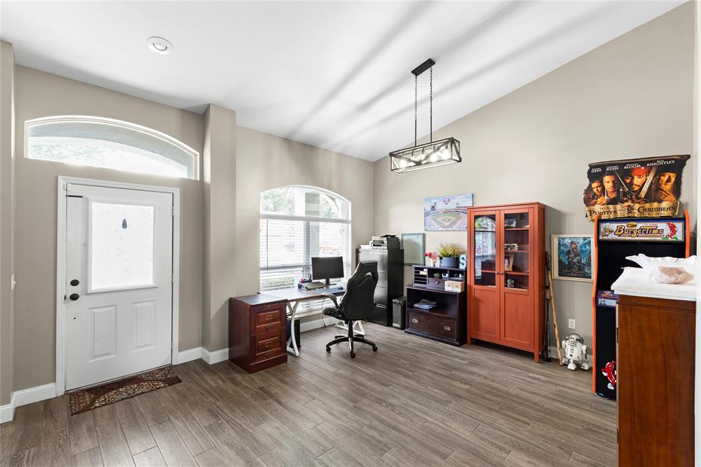 A home office with wood-look flooring, a desk, a display cabinet, and an arcade machine — 4038 LITHIA RIDGE BOULEVARD, VALRICO, FL
