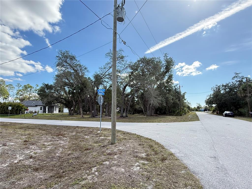 A utility pole stands at a street intersection near a wooded lot and a house — MAURBACH TERRACE, NORTH PORT, FL