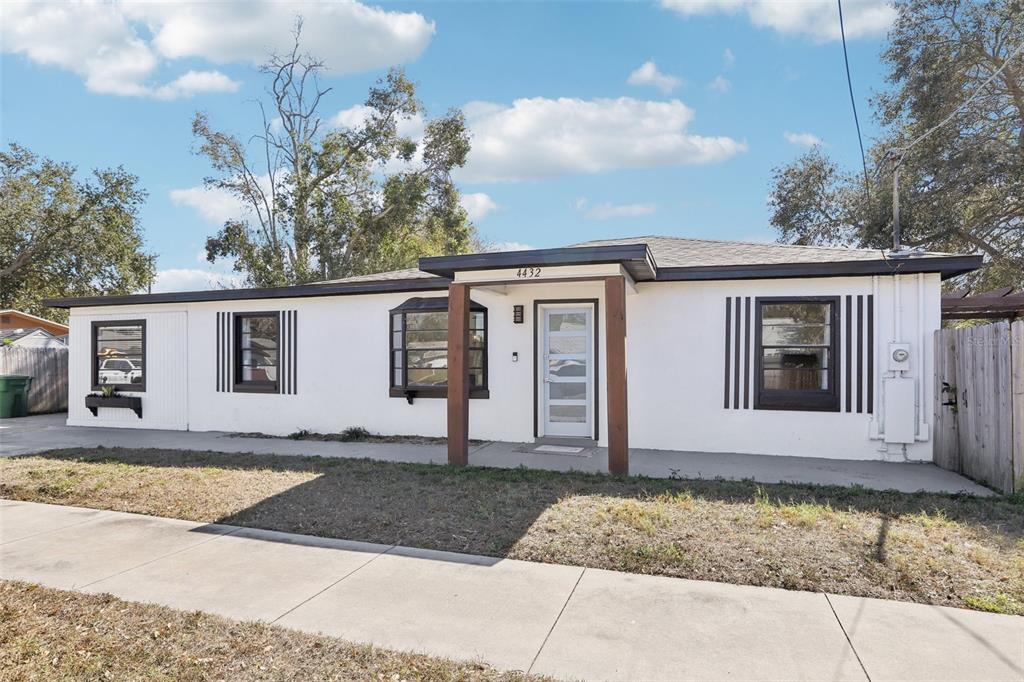 A single-story white house with dark trim and a covered front entryway — 4432 W MCCOY STREET, TAMPA, FL